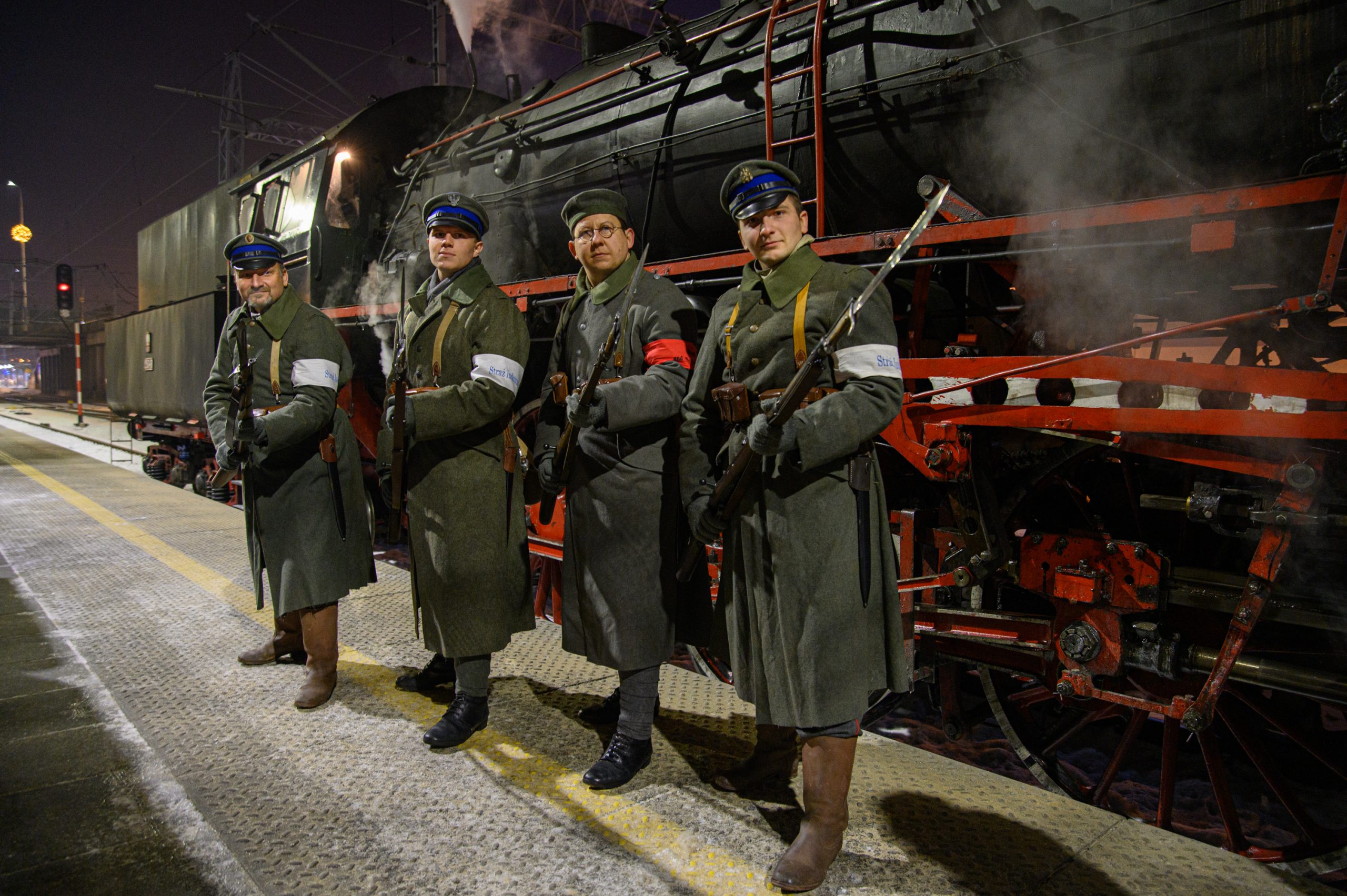 Aktorzy w strojach żołnierzy pozują do zdjęcia przed pociągiem